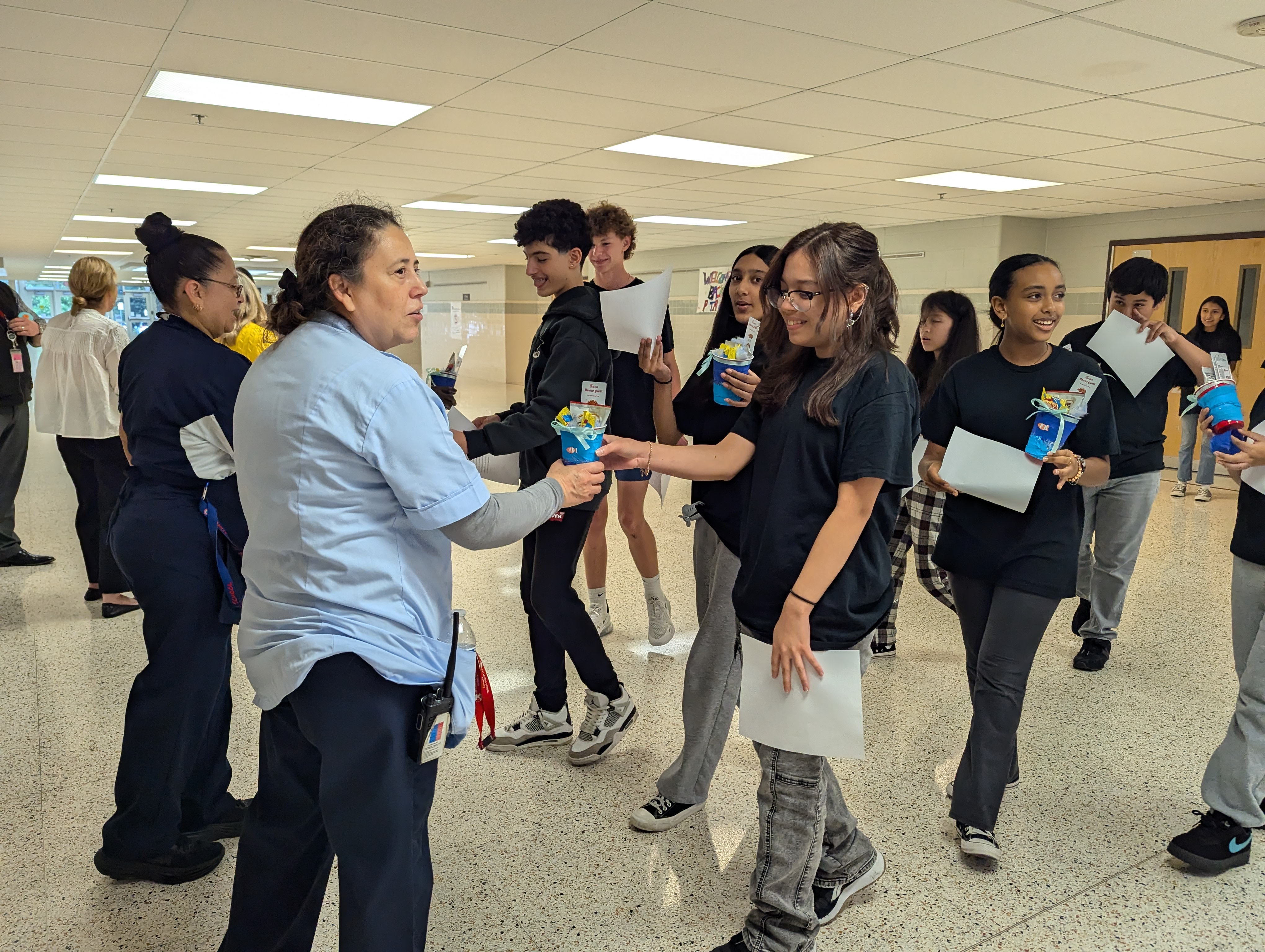 Students hand custodians small gifts after reading a poem to thank them for their hard work